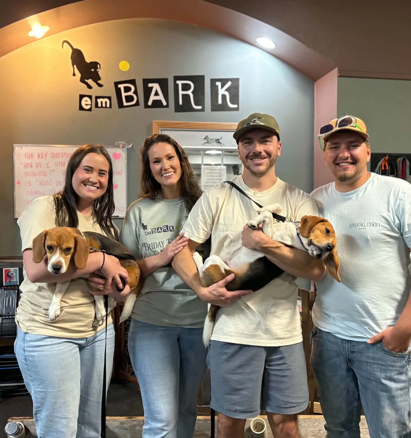 Four Finding Eden Rescue volunteers holding two beagles under an emBARK sign