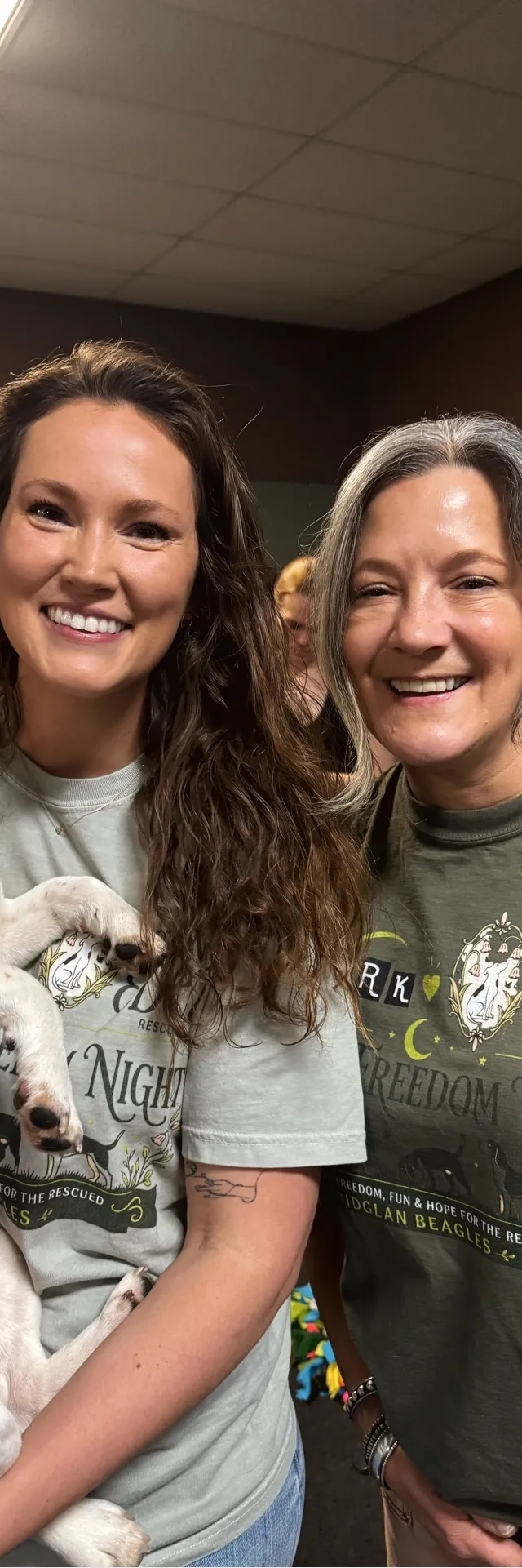 Two volunteers in Finding Eden shirts, one holding a beagle