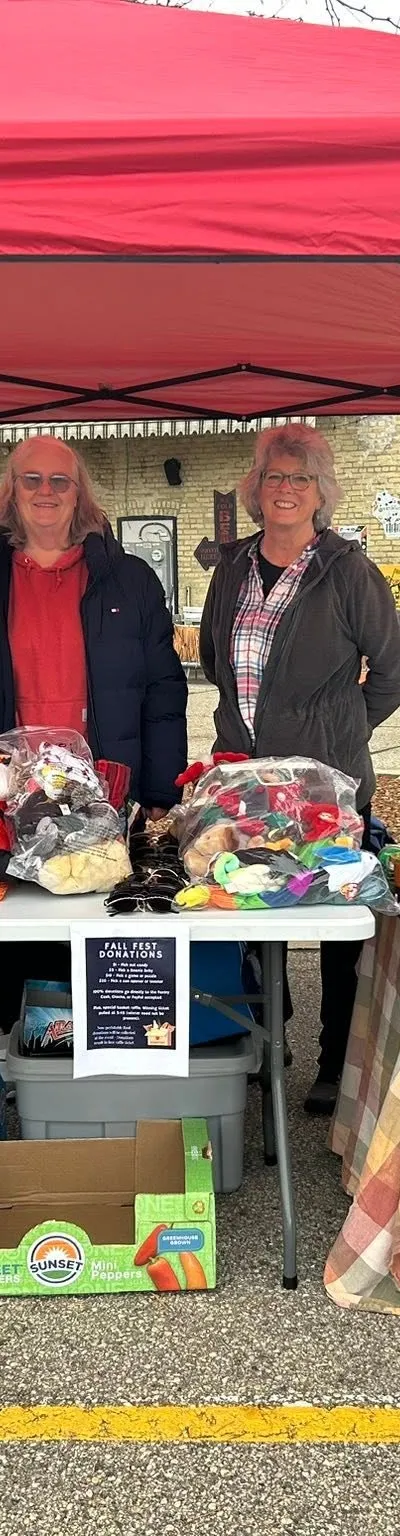 Volunteers at a Fall Fest collection table beside a Fort Atkinson Food Pantry donation barrel