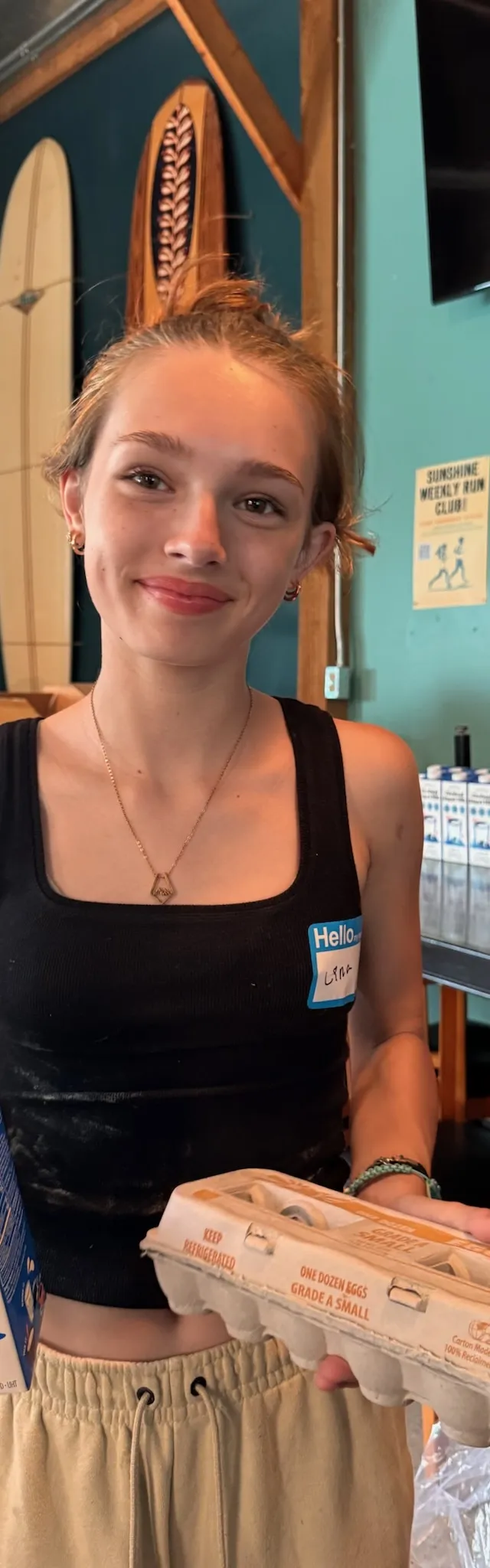 A young volunteer holding milk and a carton of eggs at the pantry