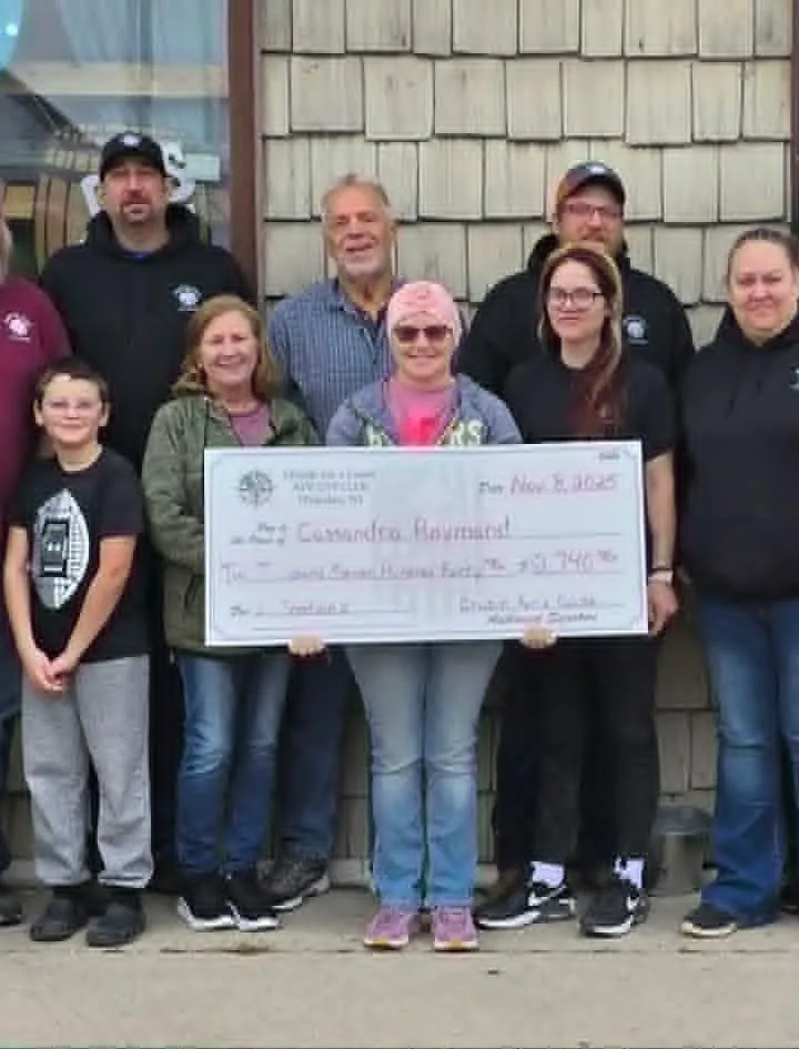 Cruzin' for a Cause members presenting a donation cheque to a family outside a Waterloo bar