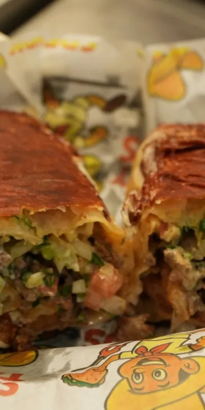 A Cali burrito cut in half, its cheese crusted tortilla shell golden and crisp