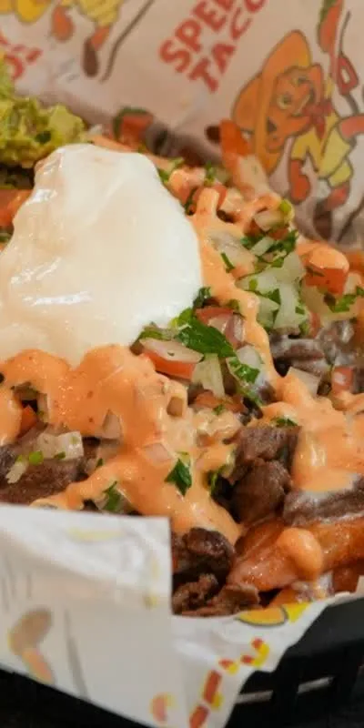 Nachos on Speedy Tacos paper with meat, crema, and guacamole