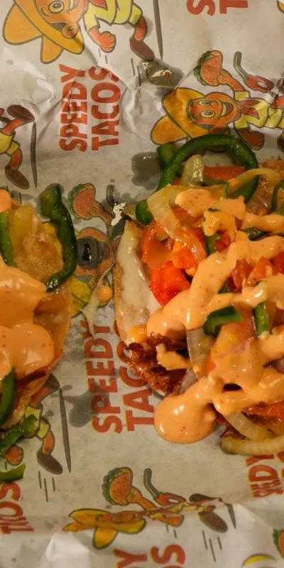 Two Baja shrimp tacos on Speedy Tacos paper with crema, jalapeno, and cilantro