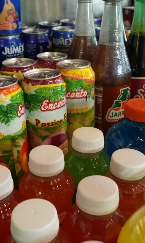 Bottles and cans of Mexican sodas and fruit juices packed onto a shelf